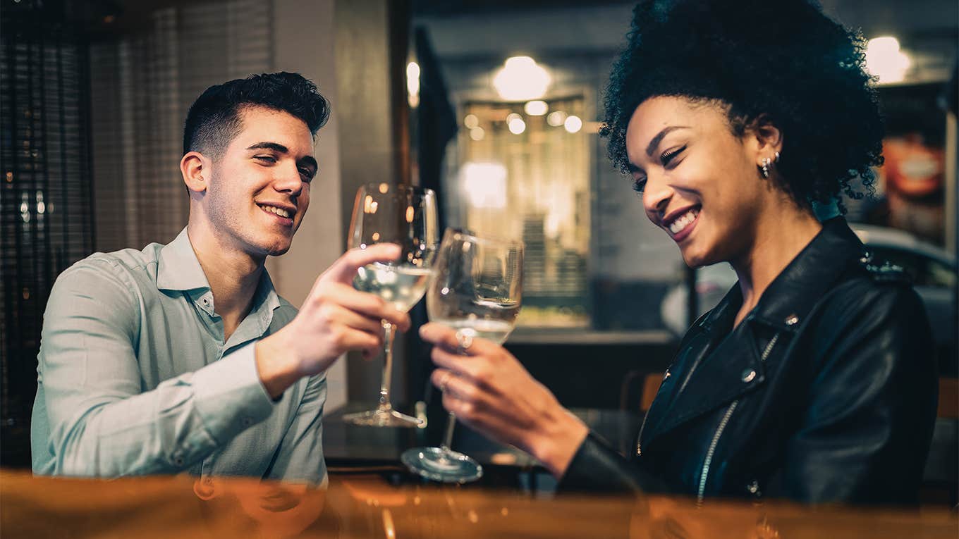 man and woman cheersing with drinks on date