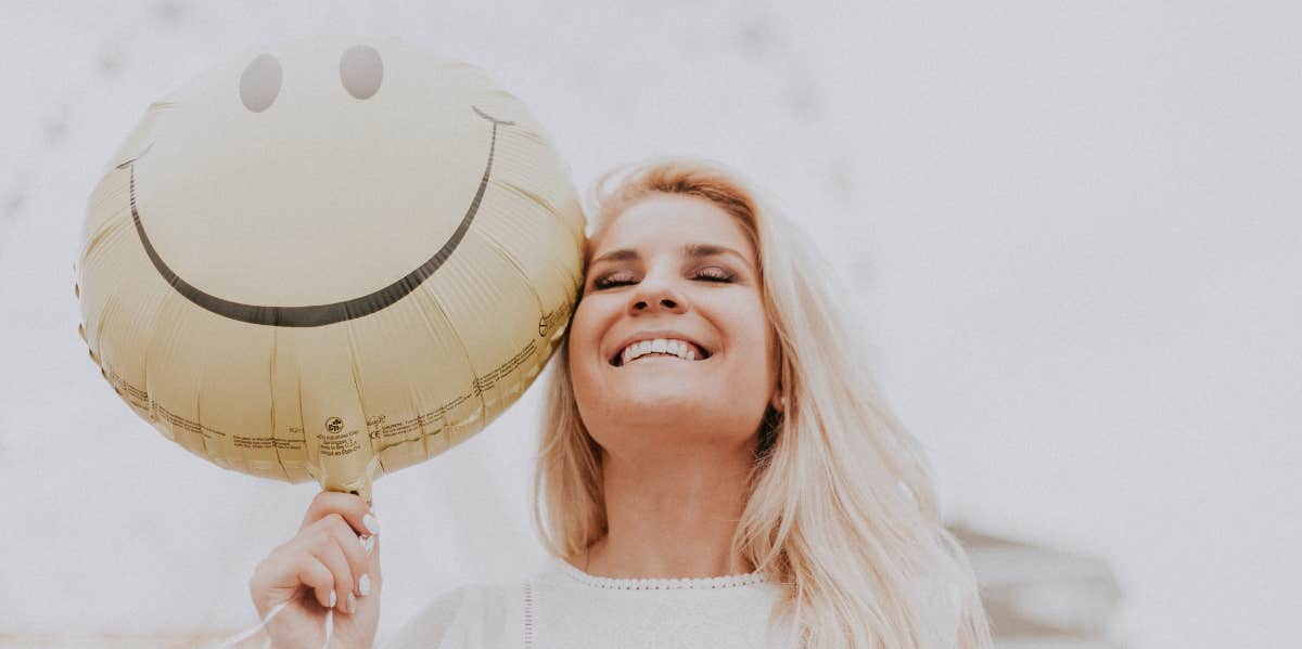 Woman with smiley face balloon looking happy and content