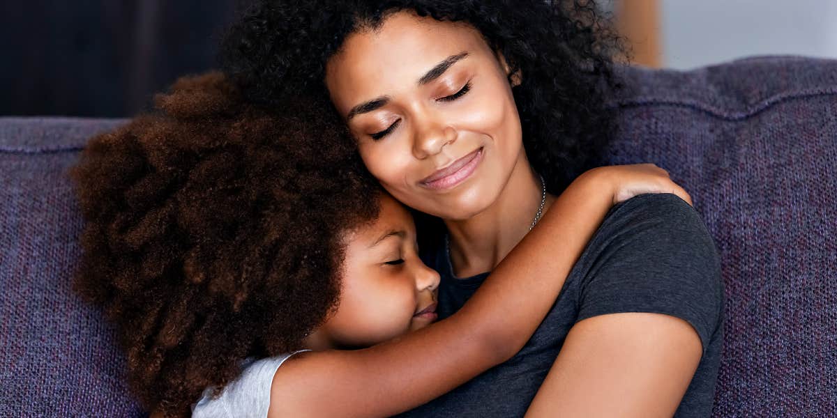 mom and daughter cuddle on couch