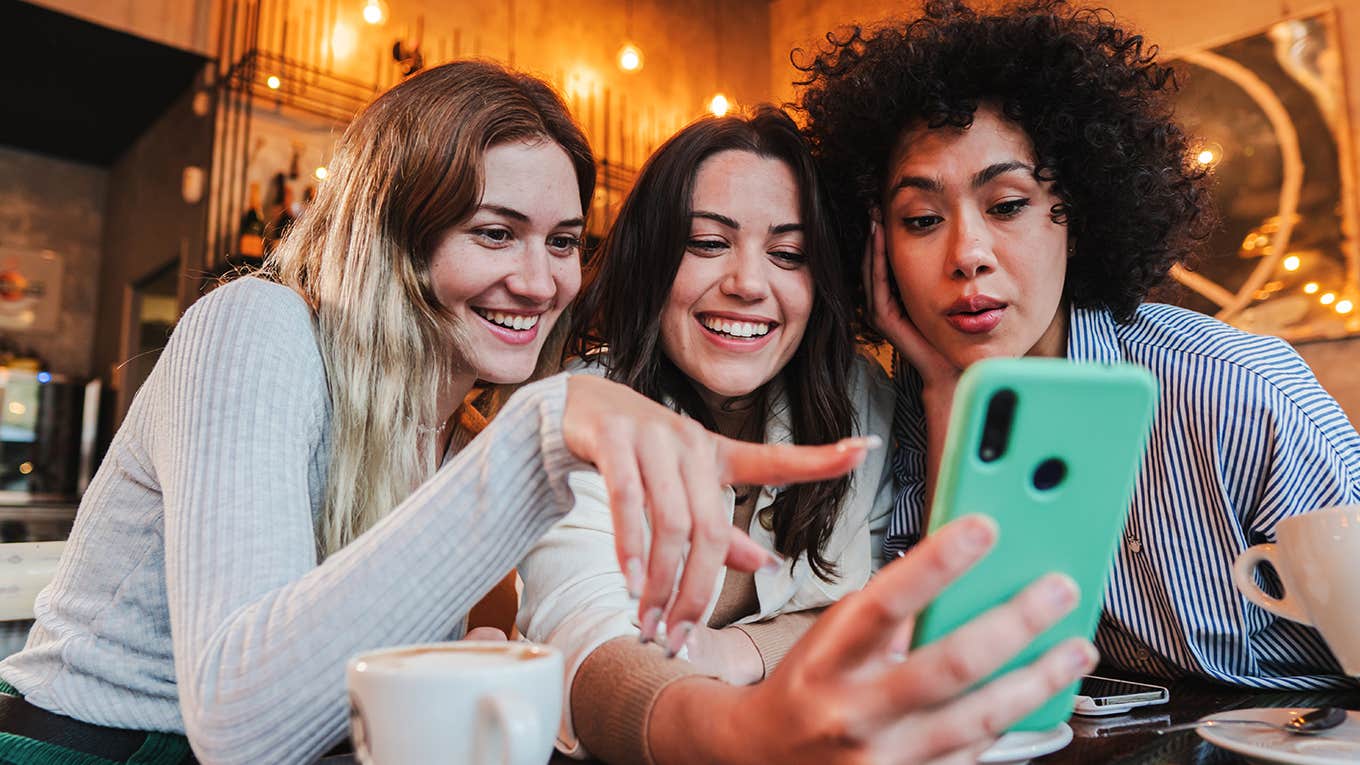 Group of young women having fun sharing media with an cellphone.