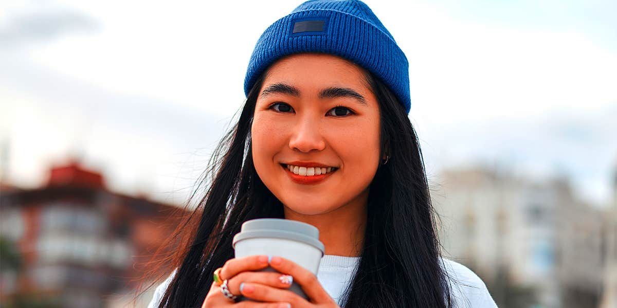woman in blue beanie holding coffee
