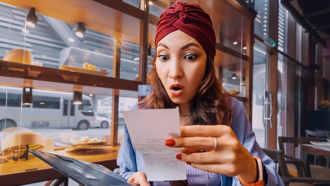 shocked woman in restaurant looking at bill