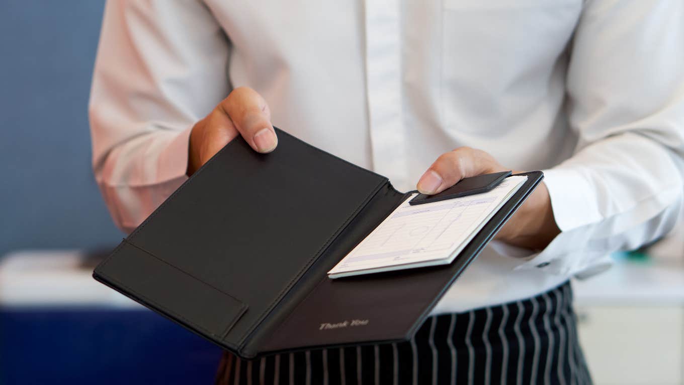Server Claims Customer Asked Him To Play A Game To Determine How Much His Tip Would Be waiter holding restaurant bill