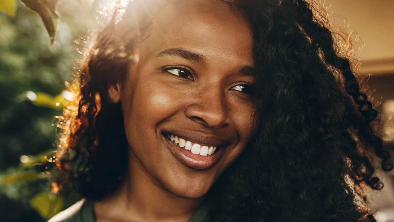 Glowing woman with natural black curls and a big smile 