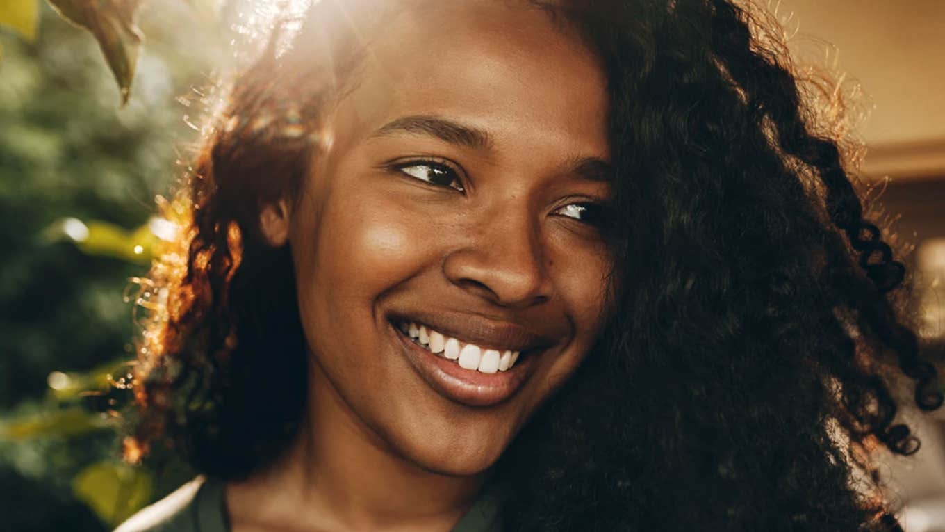 How to set goals you can realistically achieve Glowing woman with natural black curls and a big smile