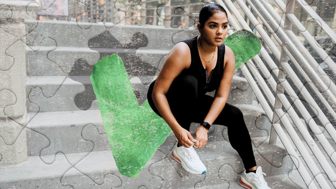 Woman sitting on steps of building lacing her gym shoes