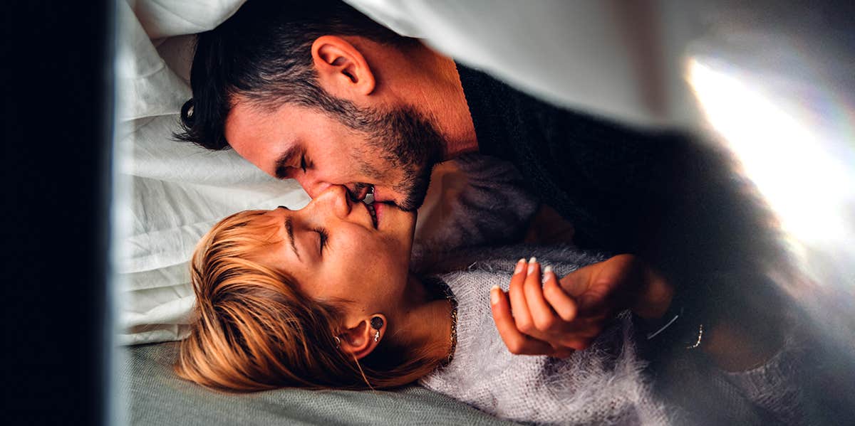 man kissing woman in bed