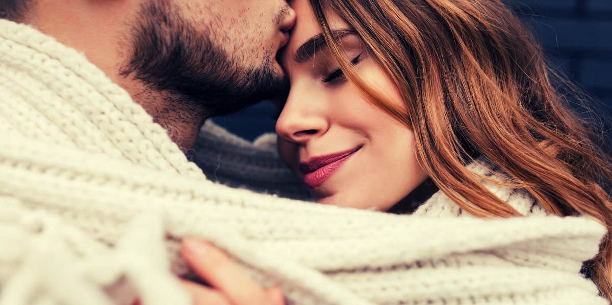 man kissing woman on forehead