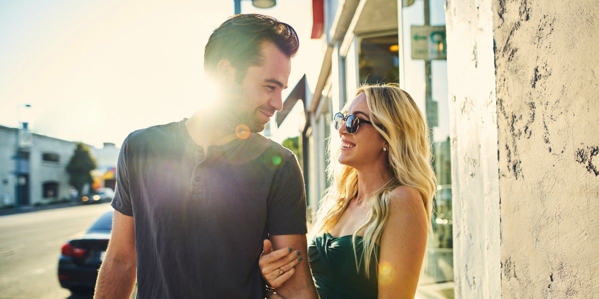 couple with lots of sexual tension flirts on the street, sun flare behind them