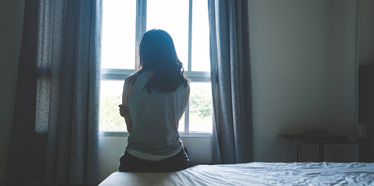 woman in shadow looking out window