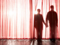 shadow of couple holding hands behind sheer red curtain