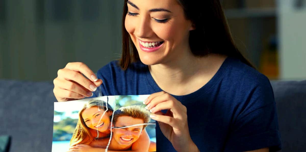 smiling woman taping back together a picture of herself and her ex
