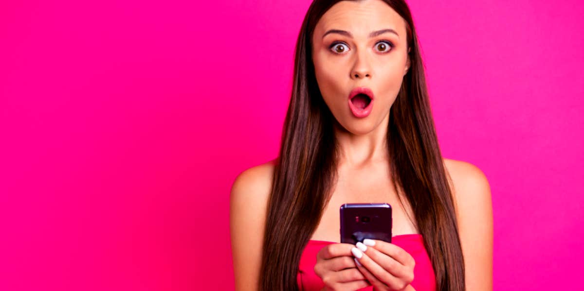 woman looking shocked after checking her phone