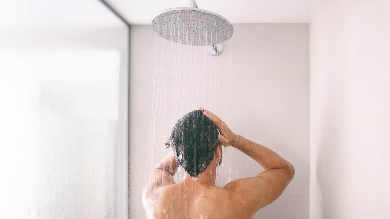 Man in the shower facing the shower head