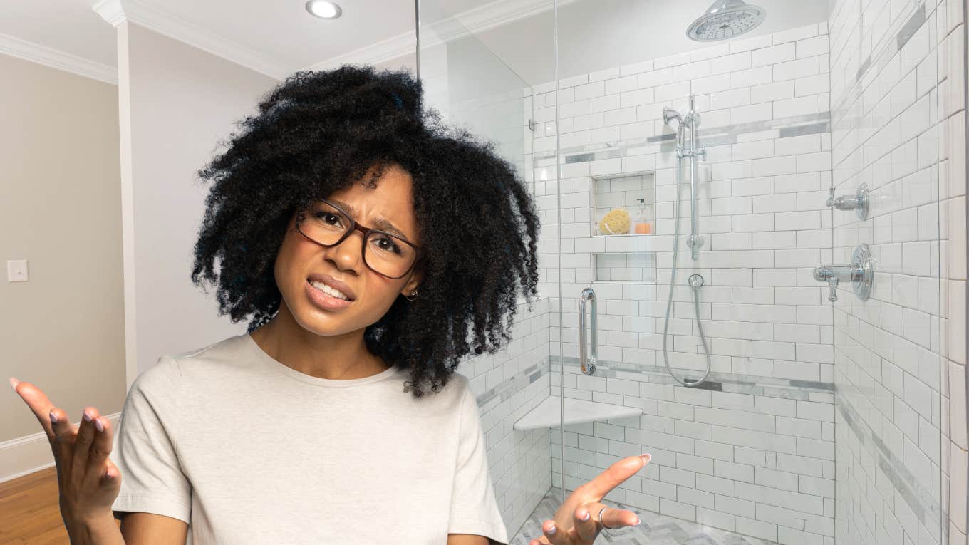 Woman with glasses looking confused next to her shower. 