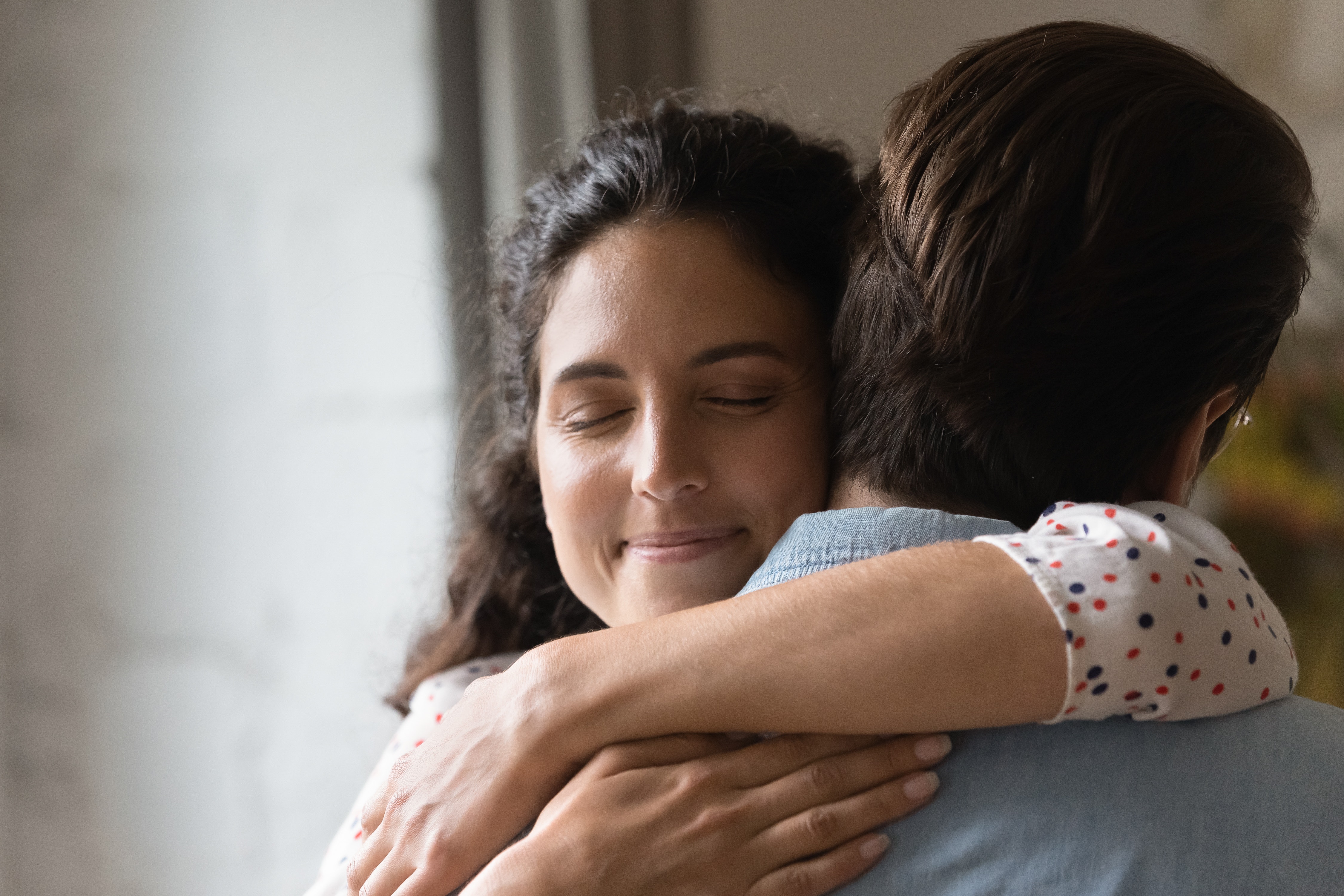 wife hugging husband with closed eyes