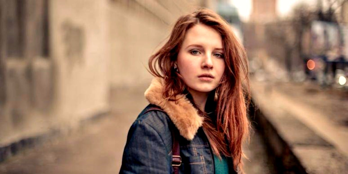 sad woman looking forward red hair jean jacket