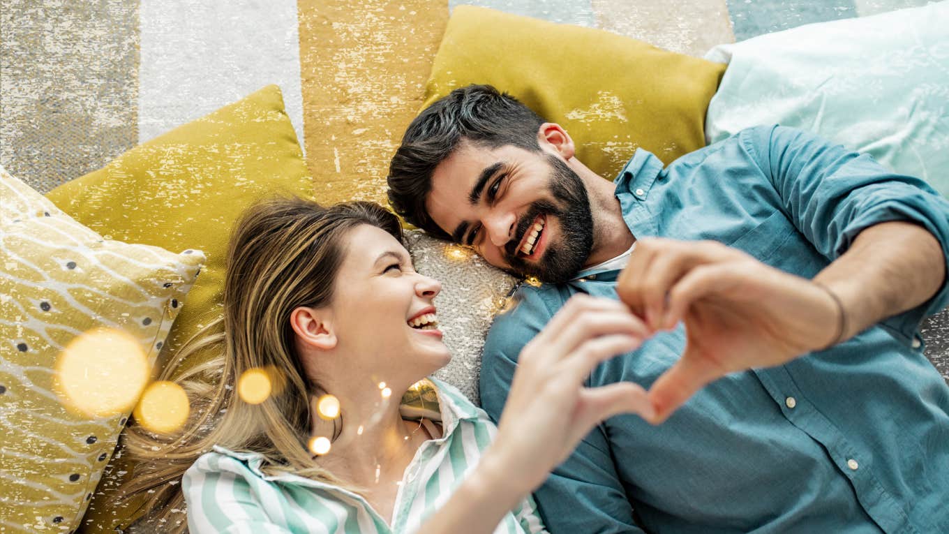 couple laying on floor making a heart with their hands