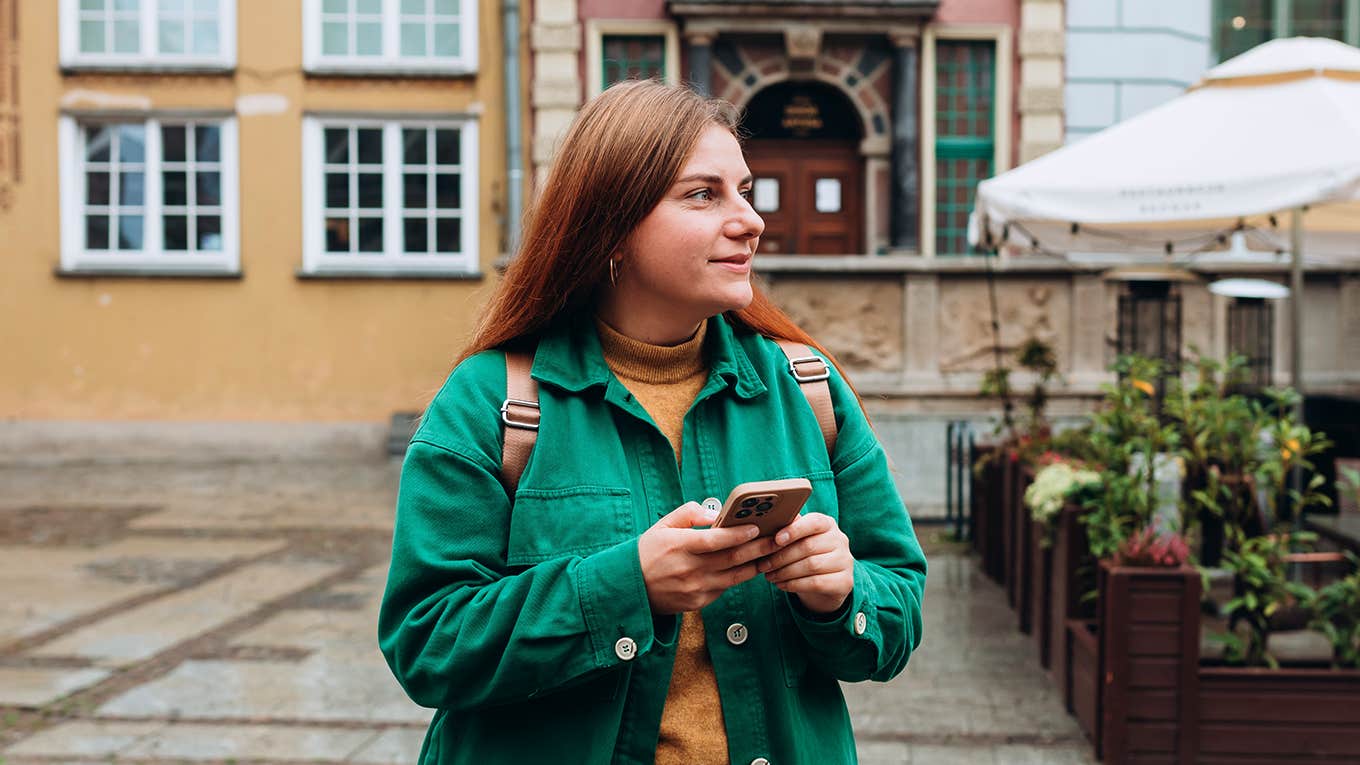 girl in green jacket holding phone