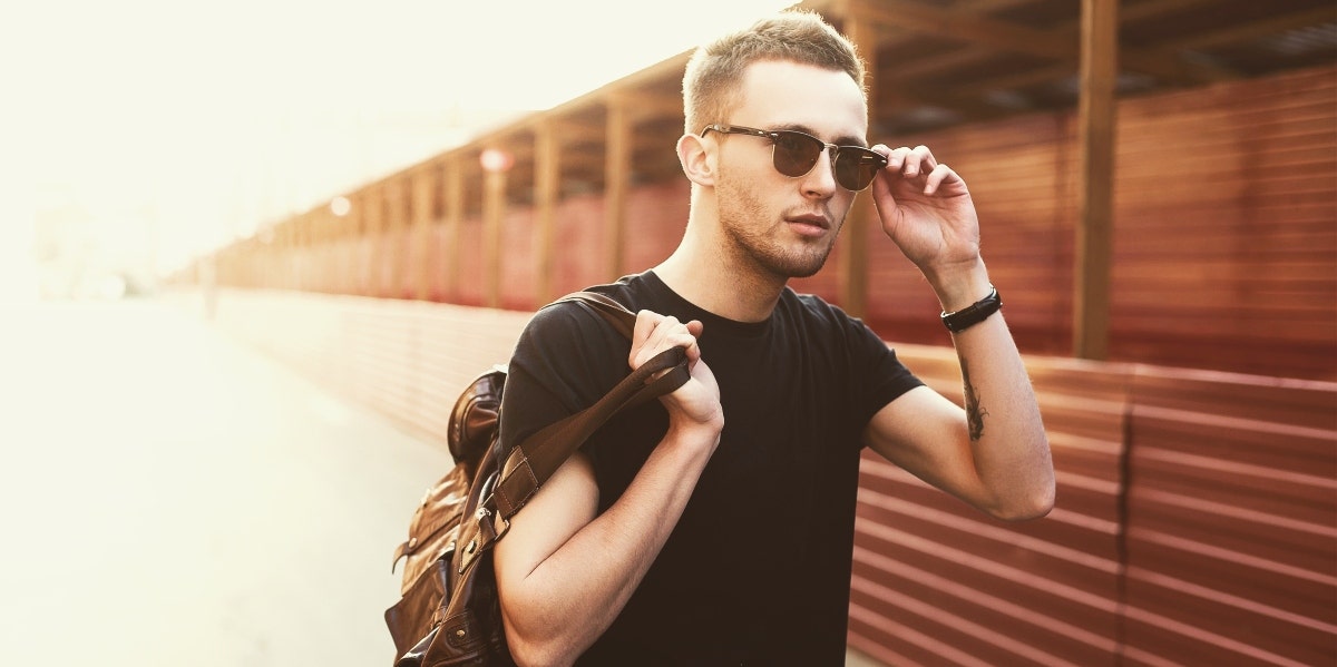 man with sunglasses on and jacket over shoulder