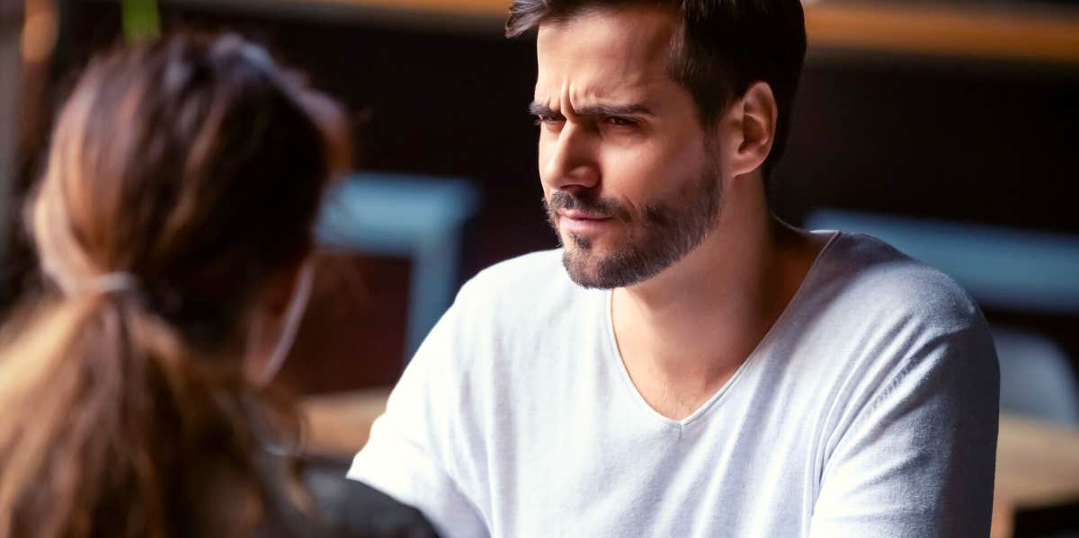 man looking unsure while he talks to a woman over coffee