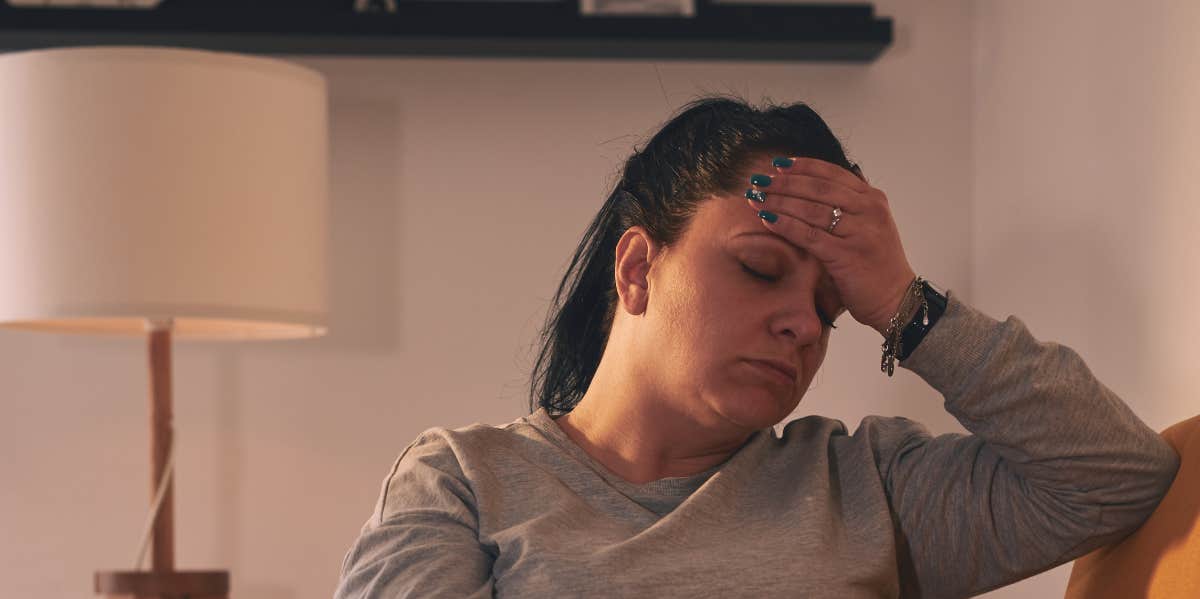 woman with hand over her face on a couch