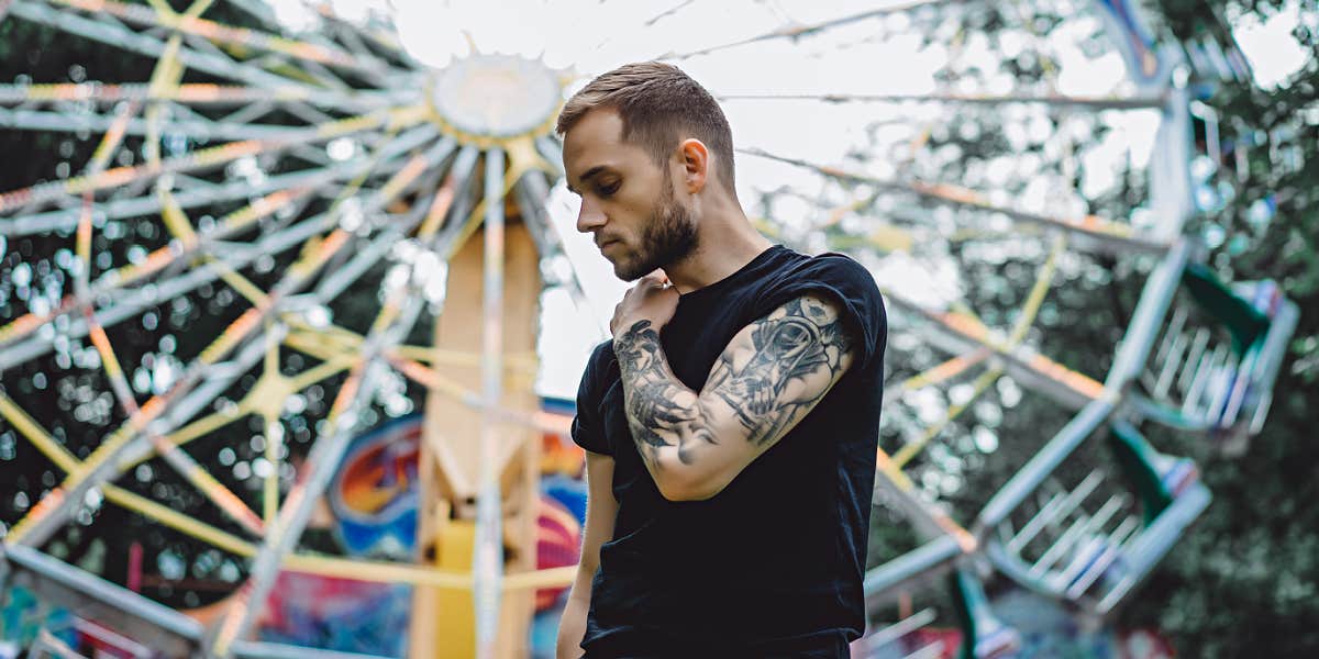 tattooed man standing in front of a Ferris wheel