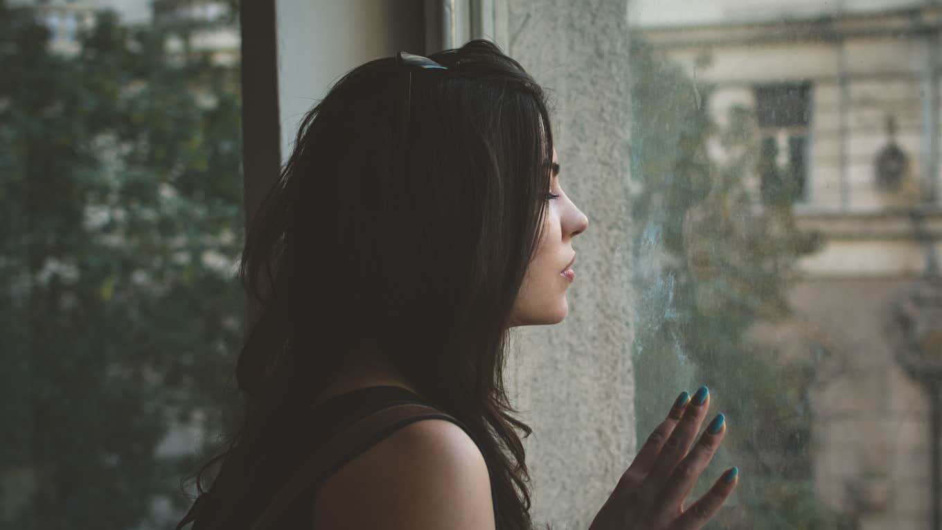 sad woman gazes outside window