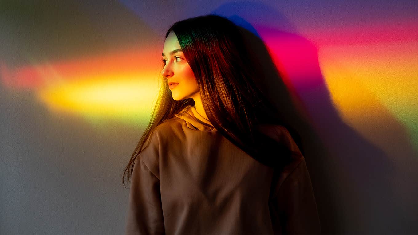 young woman side looking on glowing bright spectrum gradient.