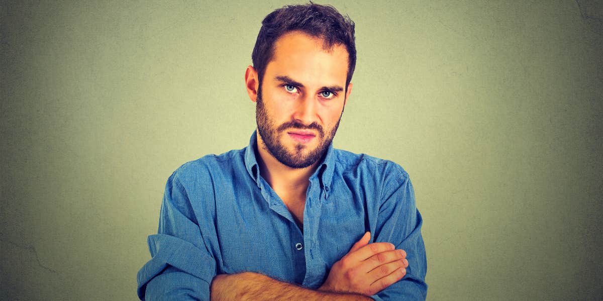 difficult man standing with his arms folded in front of his chest