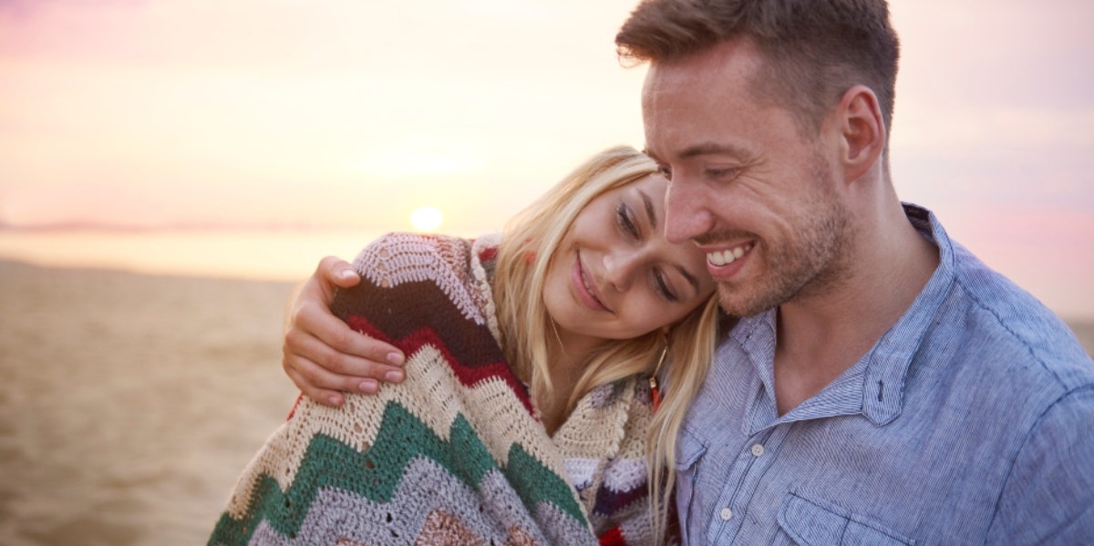 woman resting shoulder on man on the beach