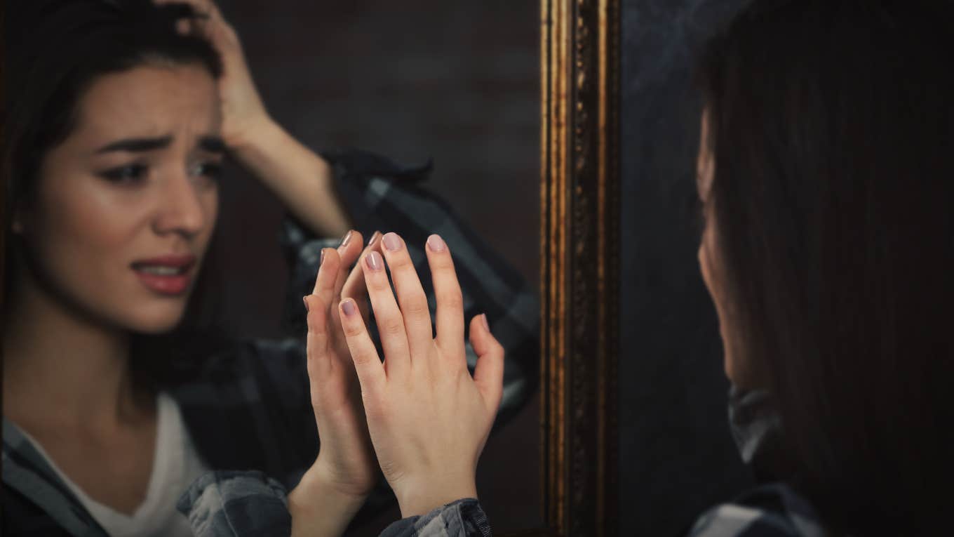 Girl looking upset at reflection in mirror 