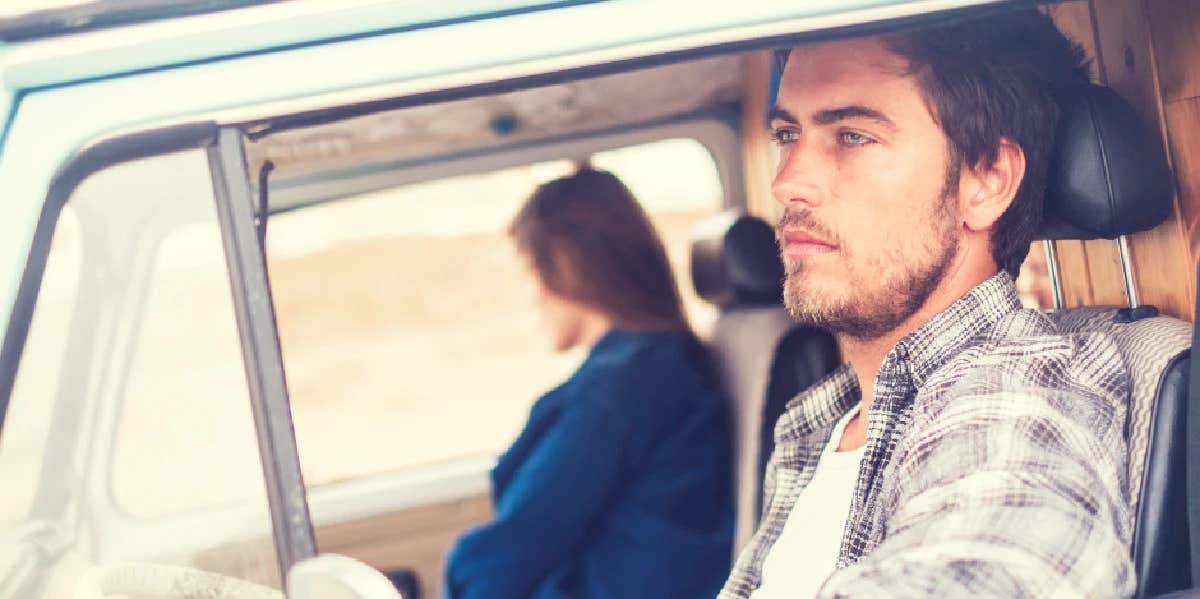 A man and woman in a vehicle look out opposite windows