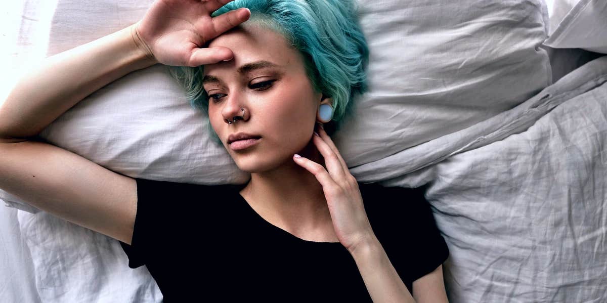 sad woman with blue hair in bed