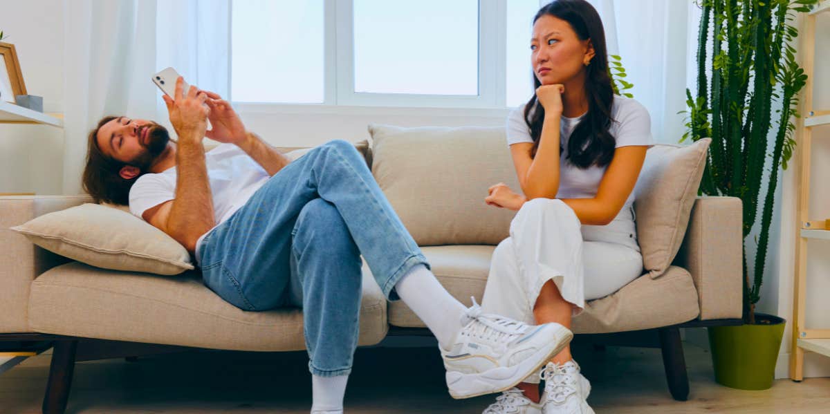 man ignoring his girlfriend while they sit on the couch