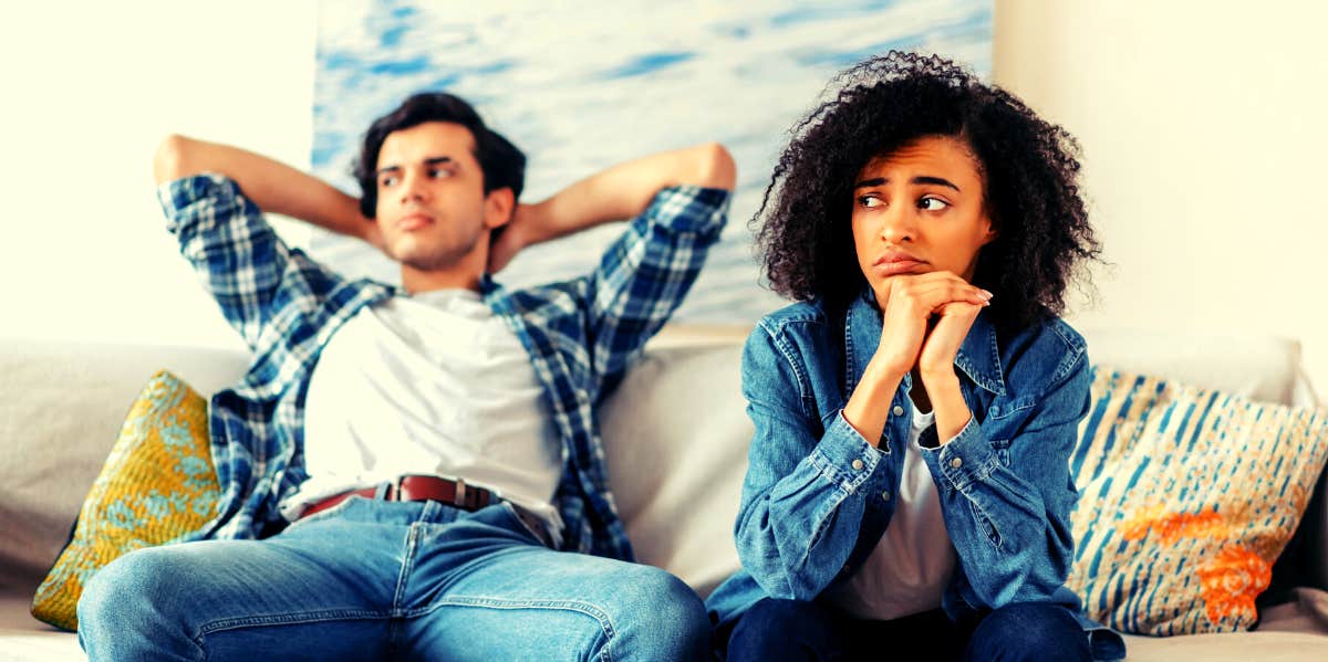 woman sitting on couch with boyfriend she knows she needs to break up with