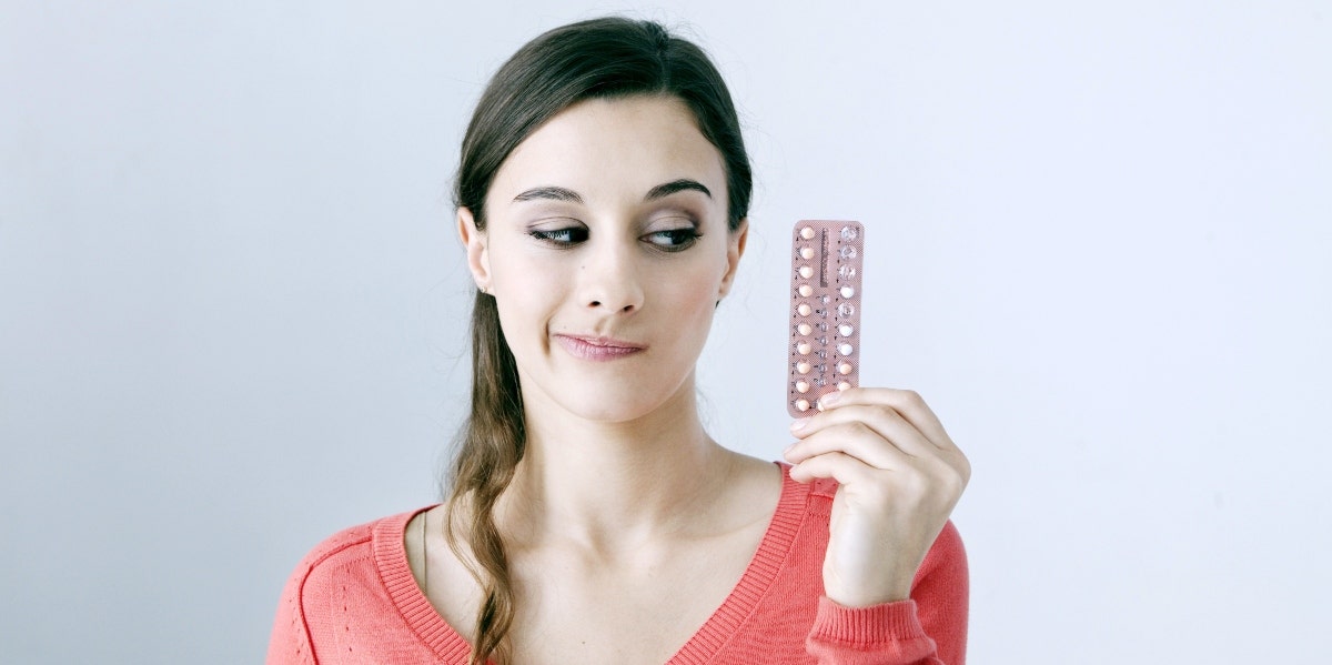 woman holding up birth control pills