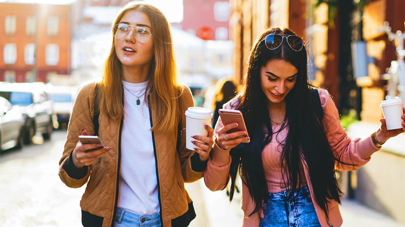 two girl best friends walking down street with coffee