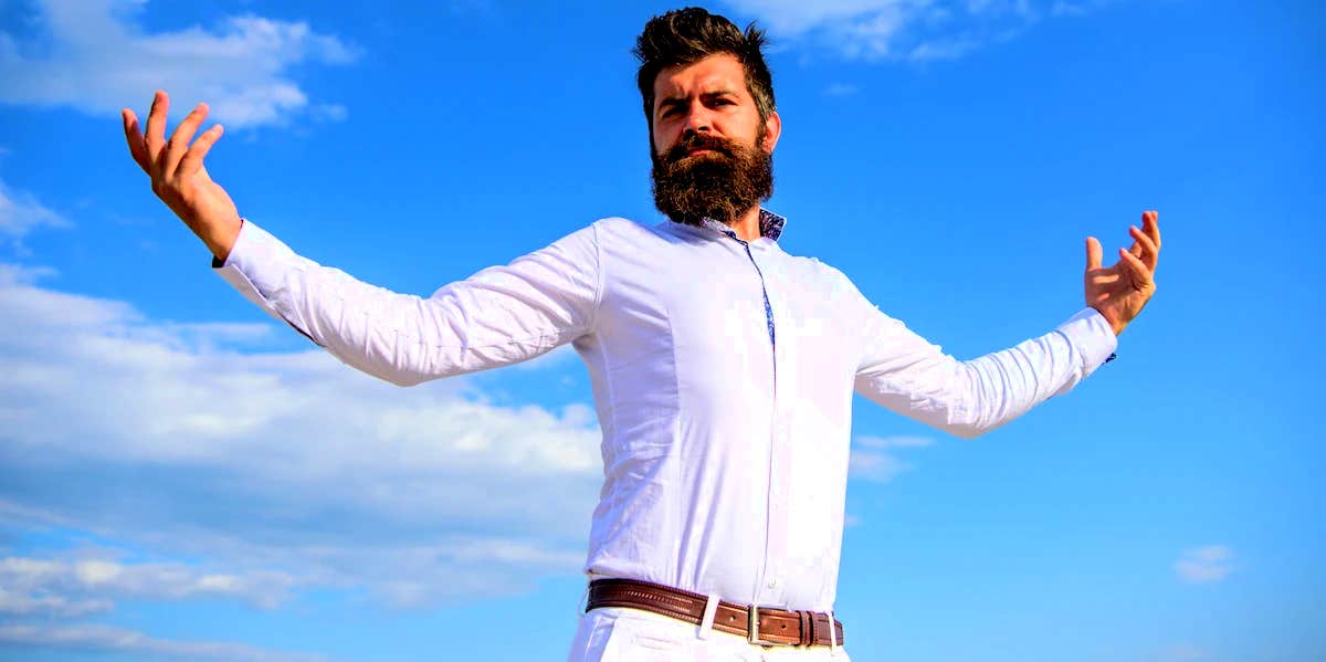 bearded man standing in front of clouds