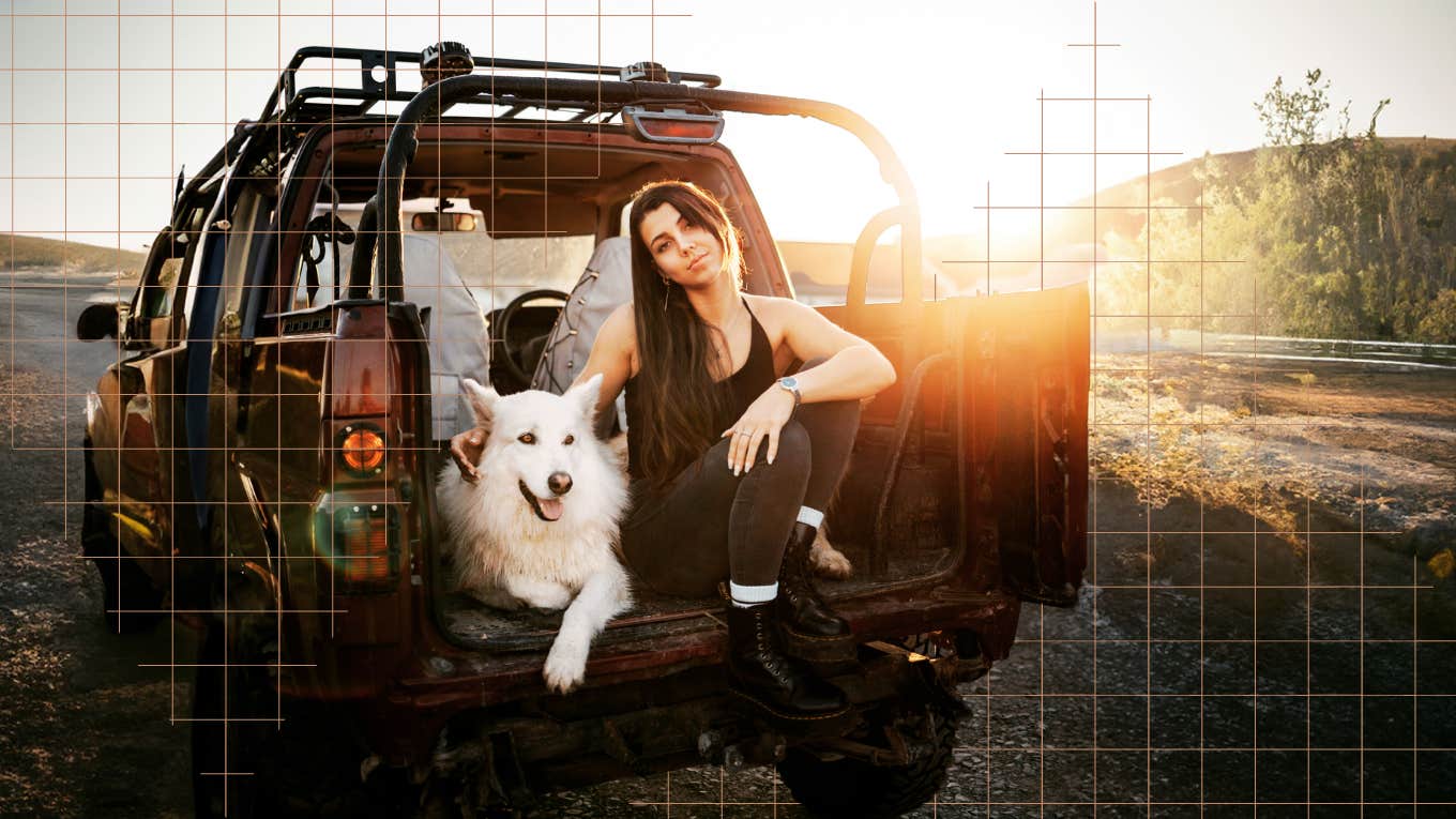 Woman sitting alone in the back of her truck with a wolf dog 