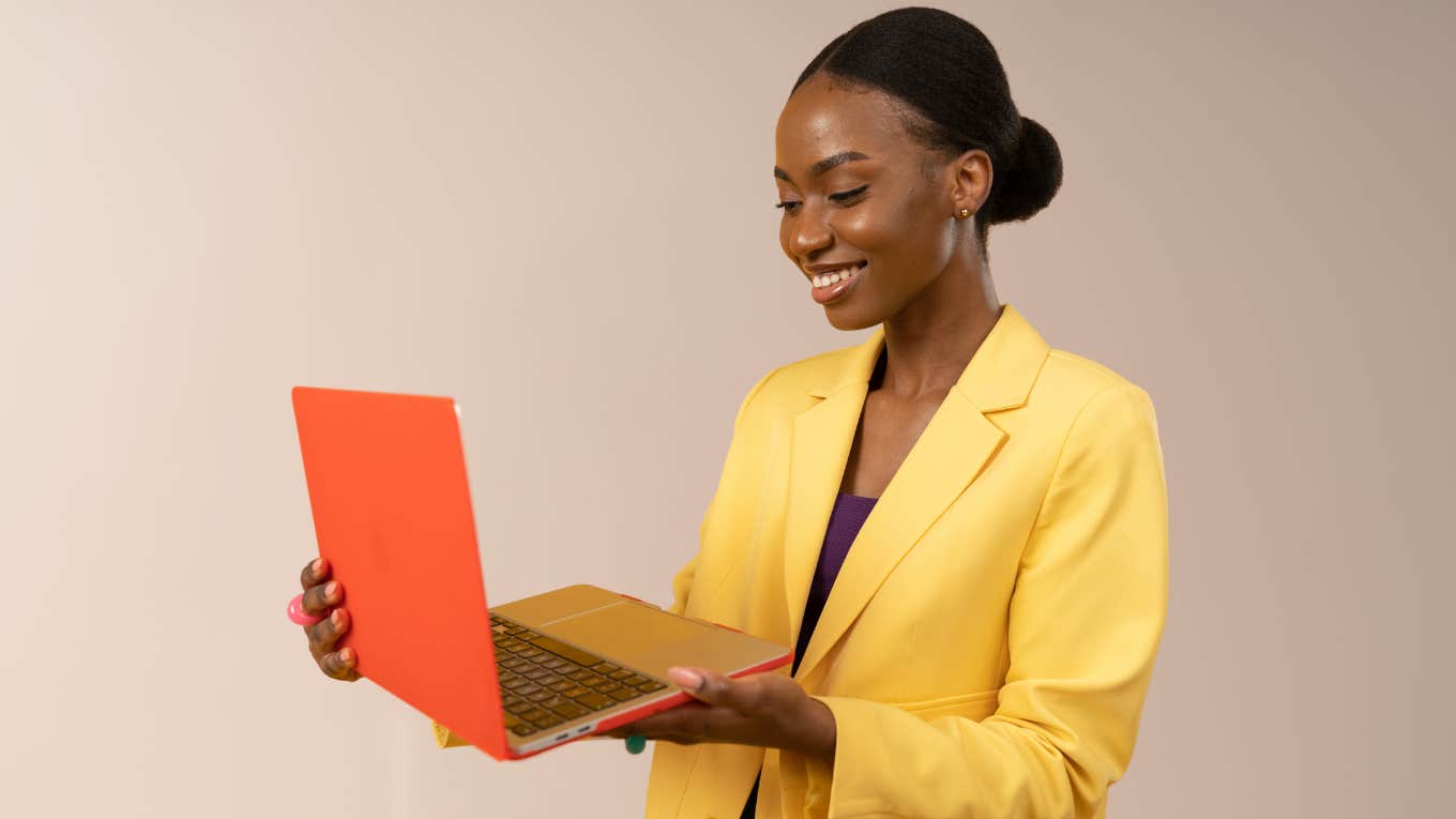Young professional woman smiling while holding her laptop. 