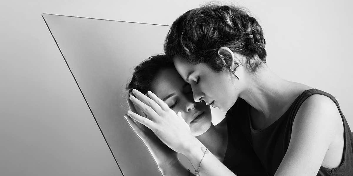 woman looking in mirror hugging self