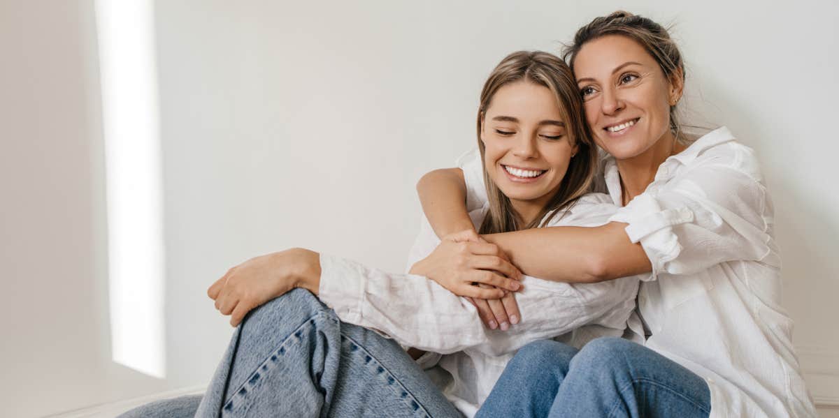 Woman hugs sister while sitting on floor