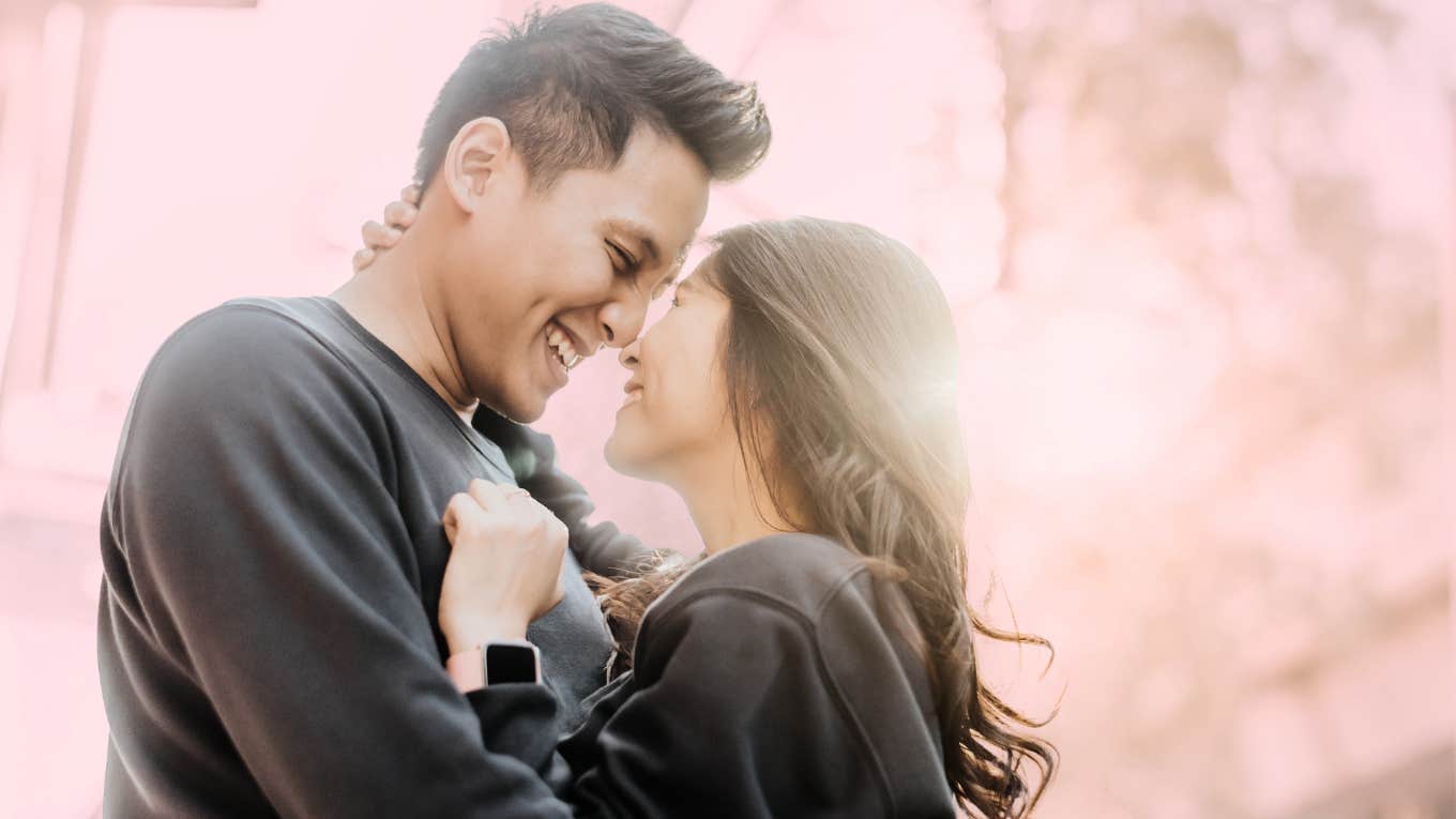 Man and woman smiling and hugging each other closely. 