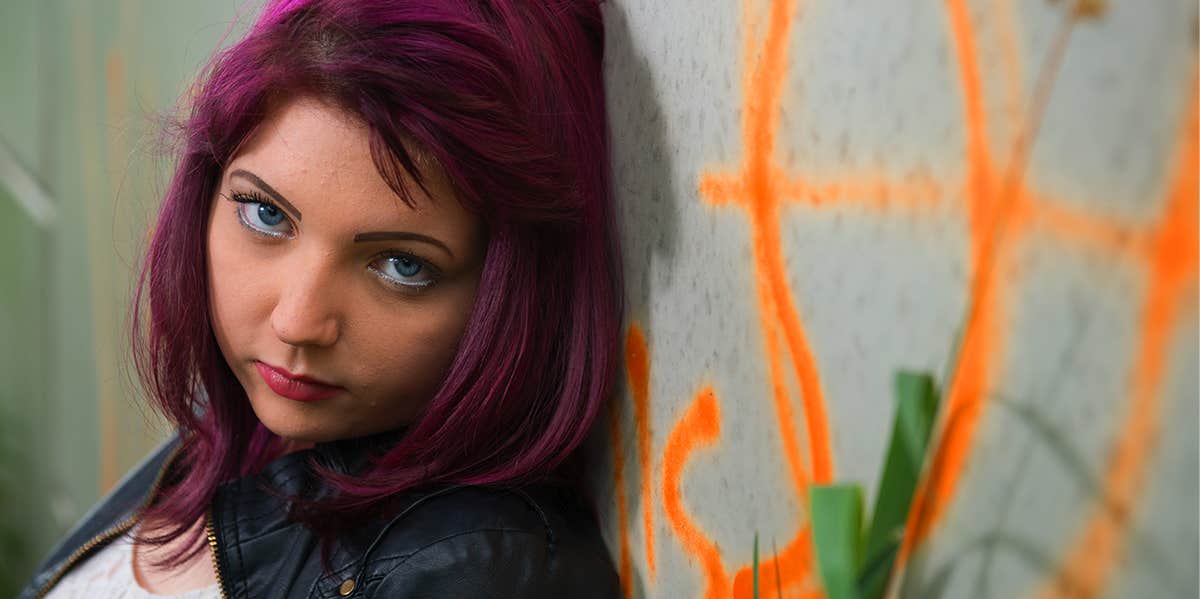 teen girl standing against a wall