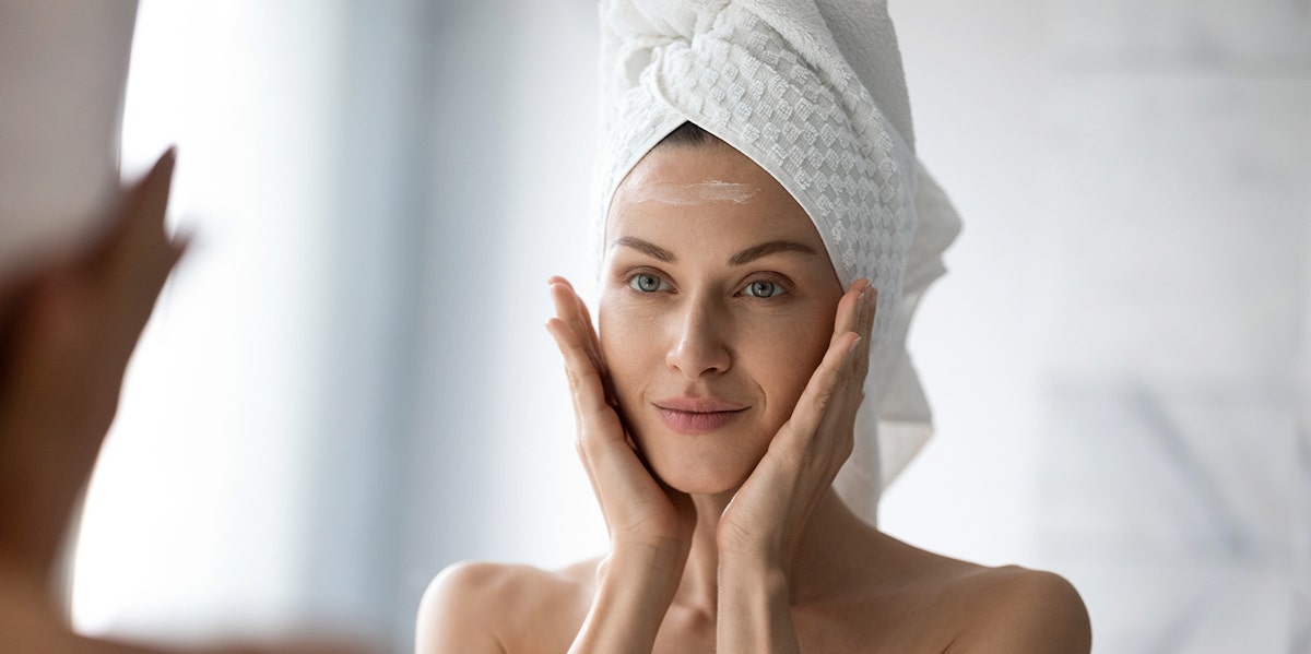woman looking in mirror with towel on her head