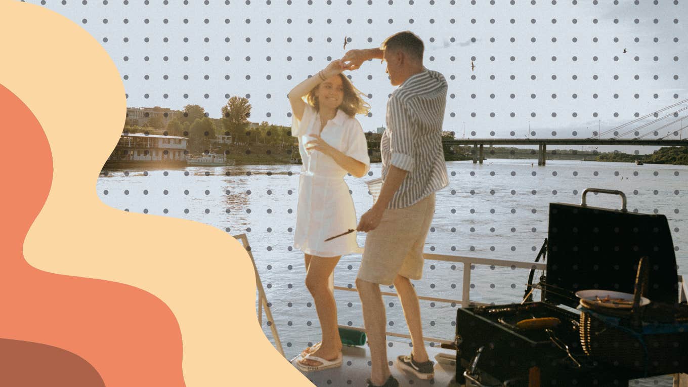 Couple dancing on pier while grilling dinner at sunset