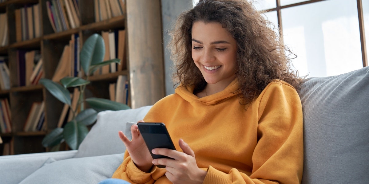 social media best practices woman in yellow sweater on her phone