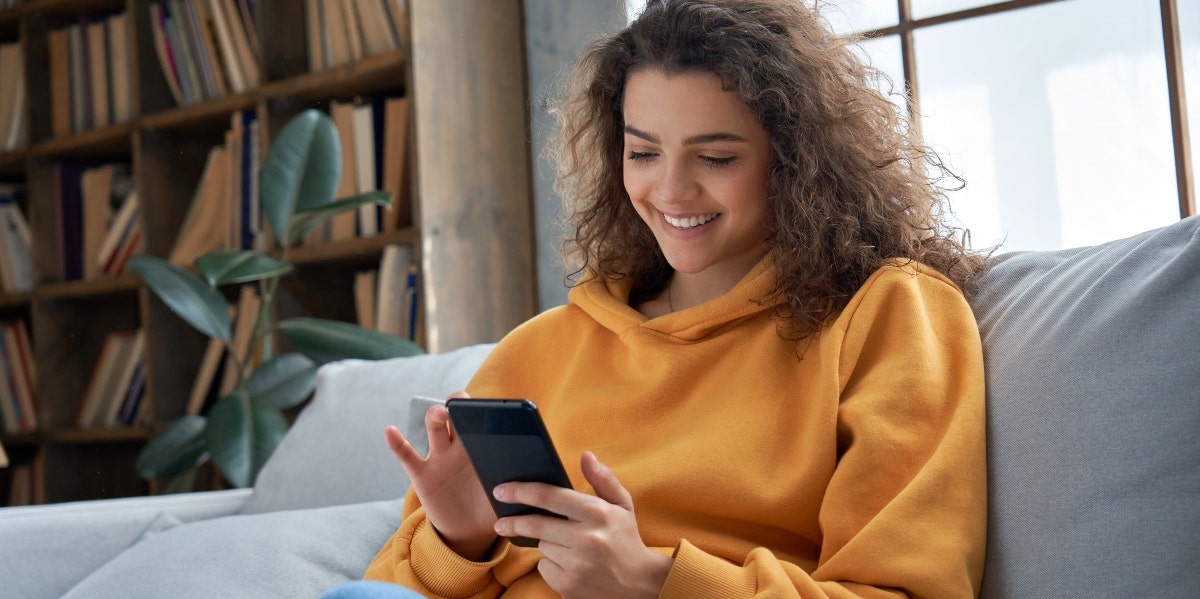 woman in yellow sweater on her phone