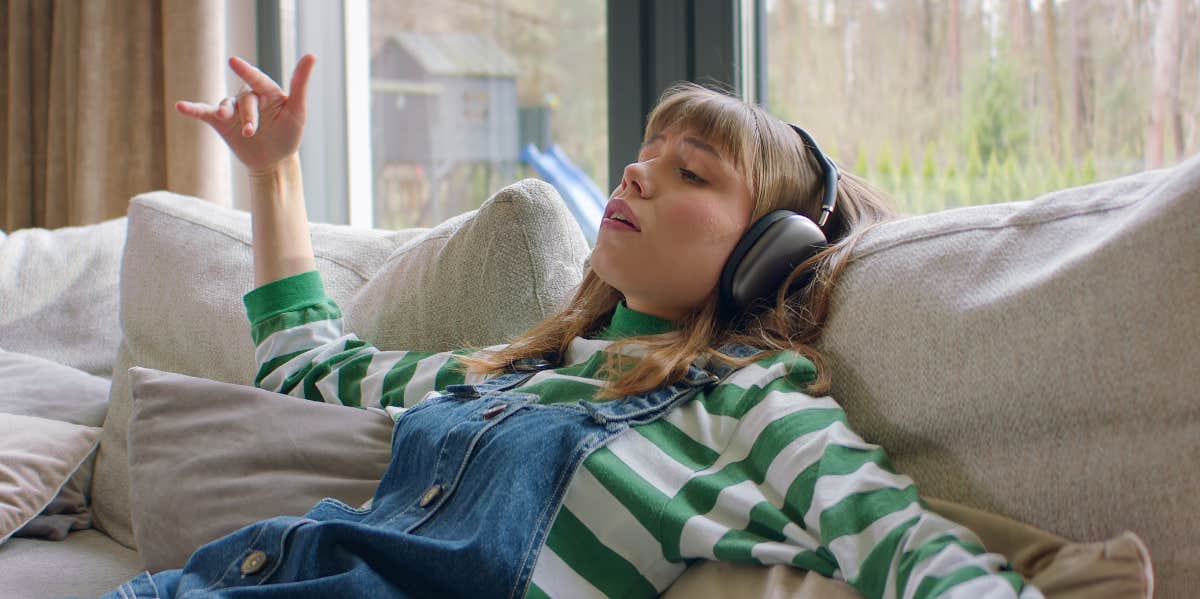 The Most Relaxing Song In The World, According To Research woman listening to music on a couch